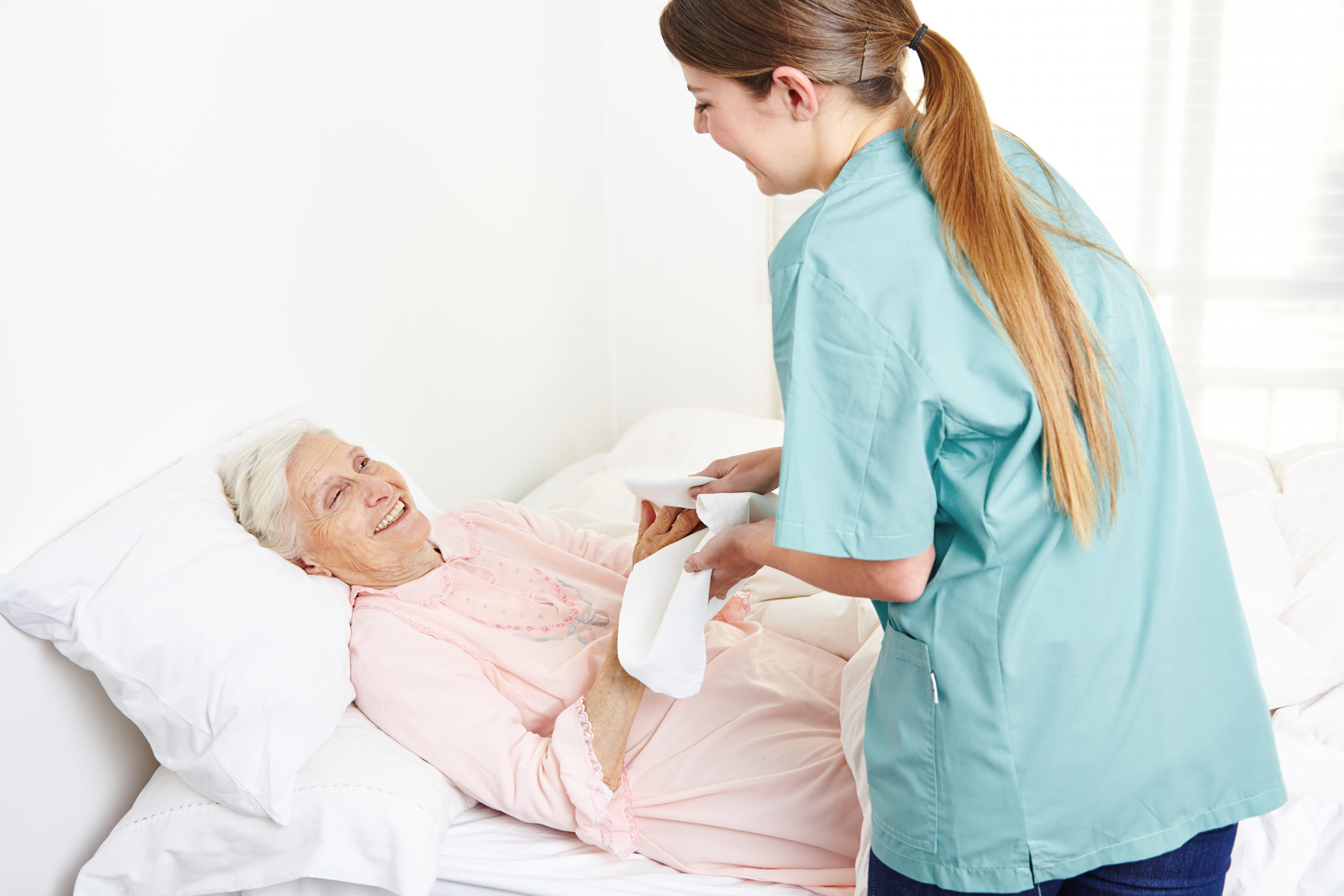 geriatric nurse washing bedridden senior woman